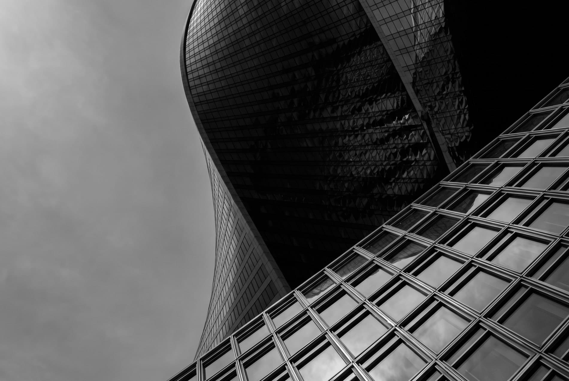 A sculptural glass tower rising against an overcast sky.